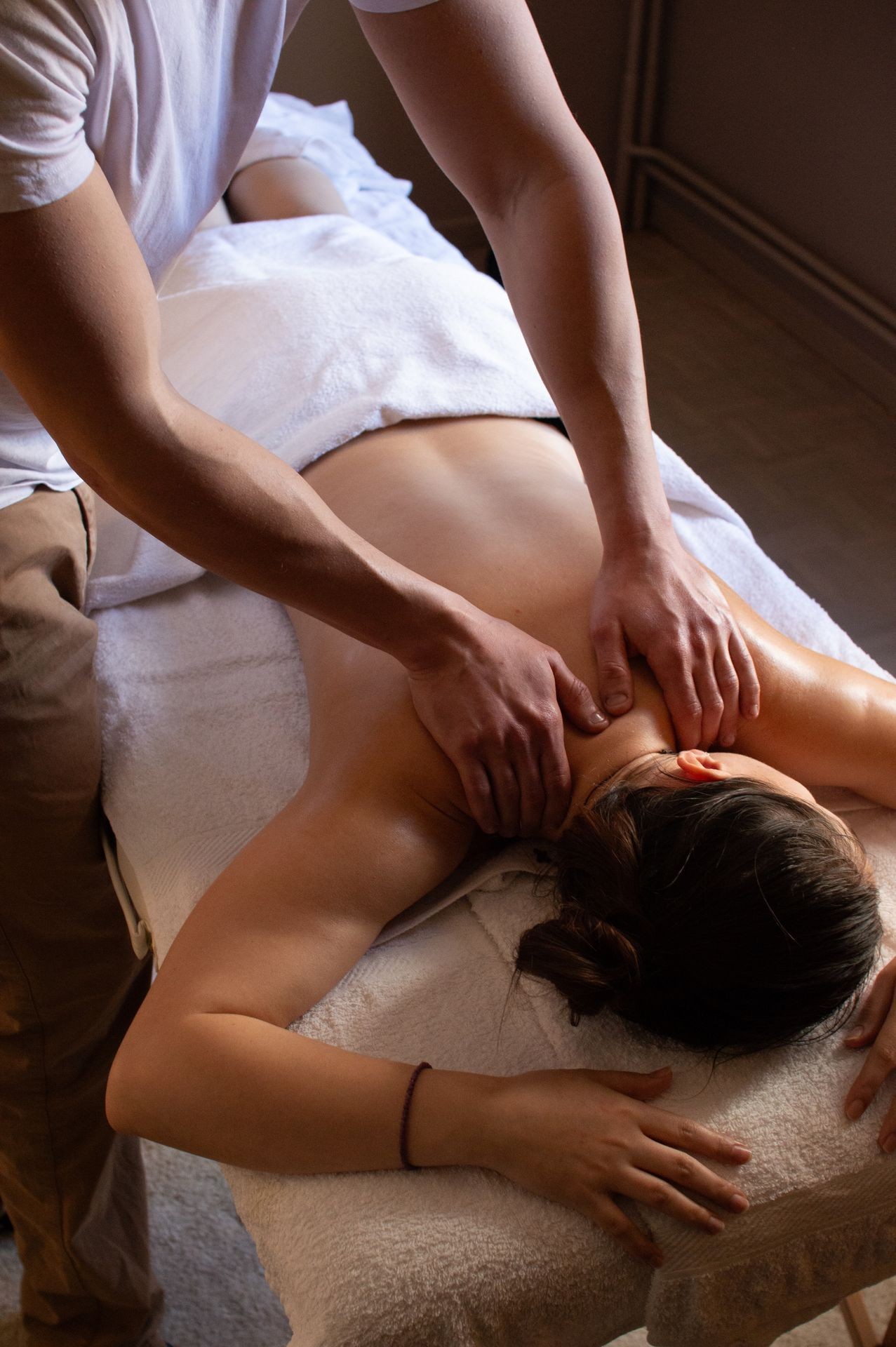 Person receiving a relaxing back massage while lying on a massage table covered with white towels.